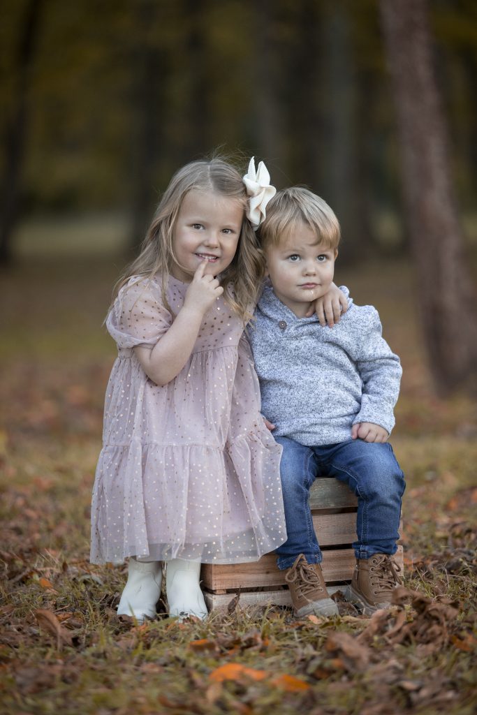 two kids sitting on a crate in the woods